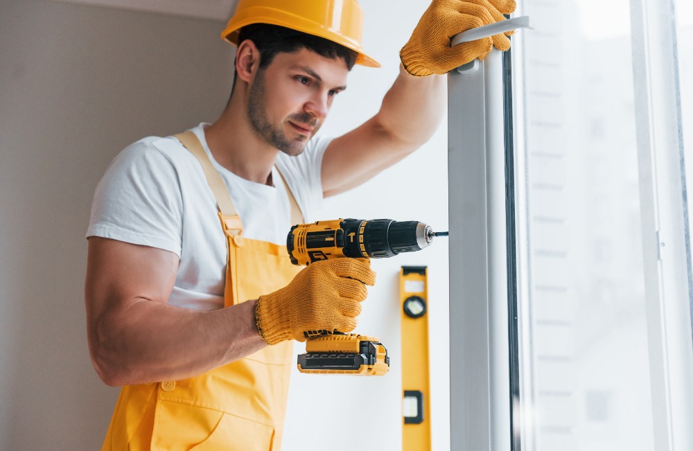 Mann repariert Türschloss und nutzt eine Bohrmaschine.